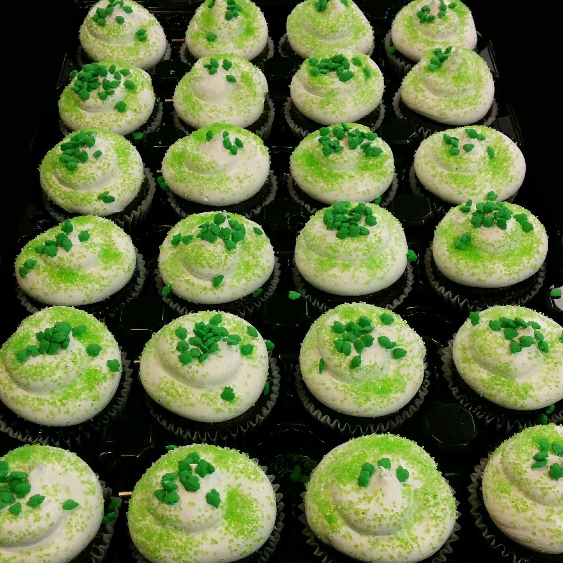 A tray of cupcakes topped with green sprinkles.  Because you can't have a holiday without cupcakes. 